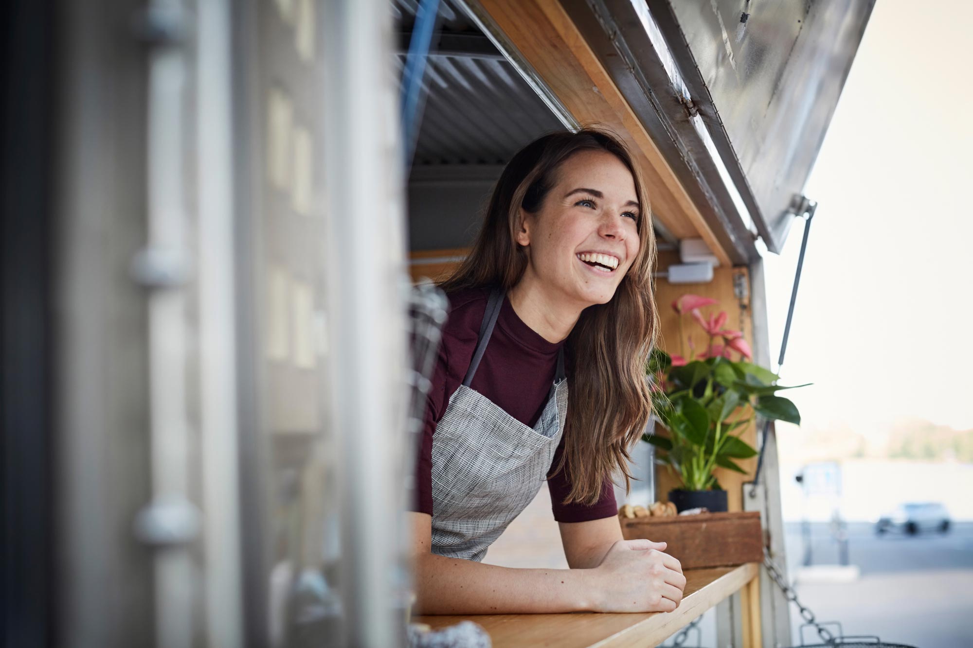 Kvinna som tittar ut ur sin foodtruck och ler