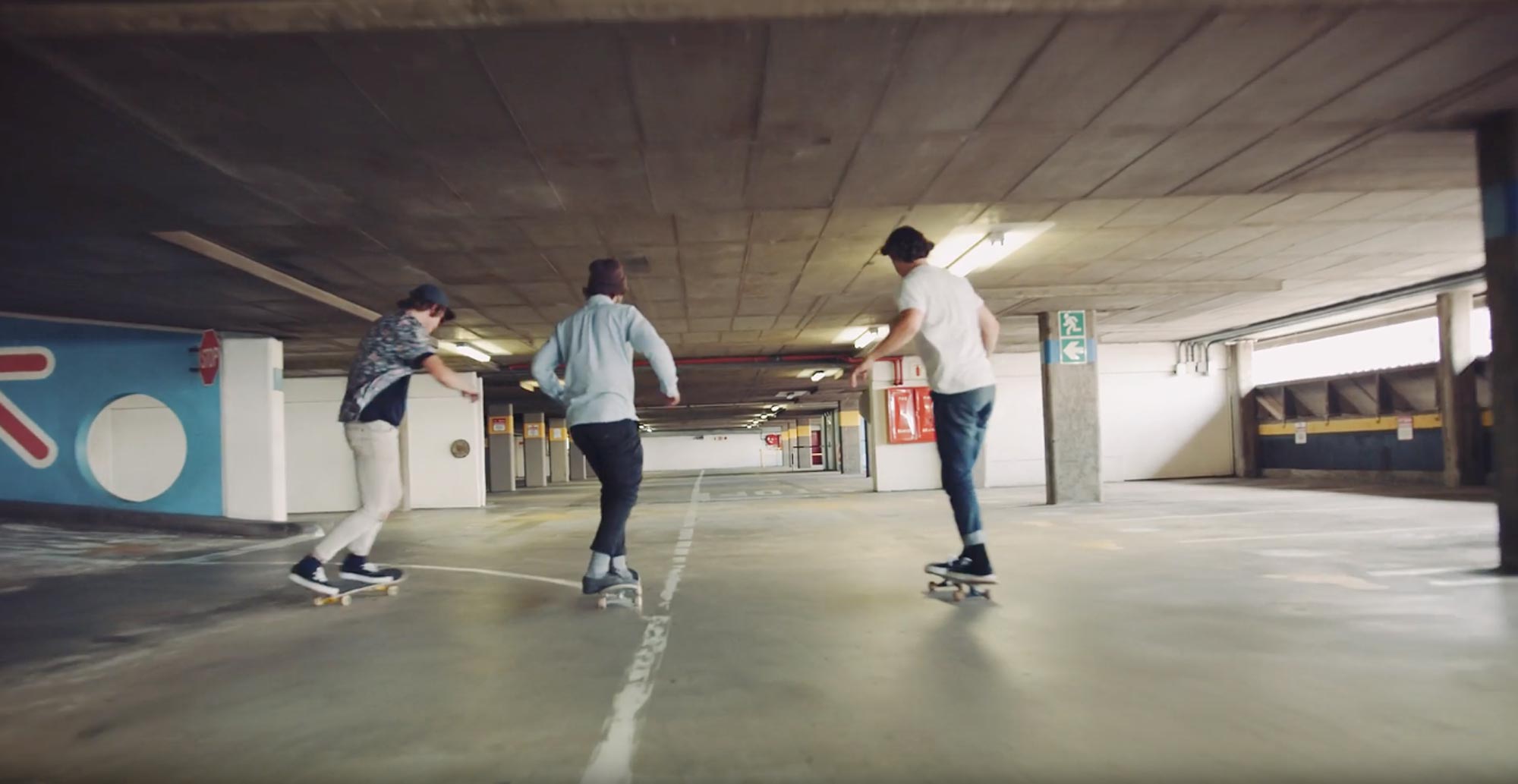 Tre personer åker skateboard i ett parkeringshus