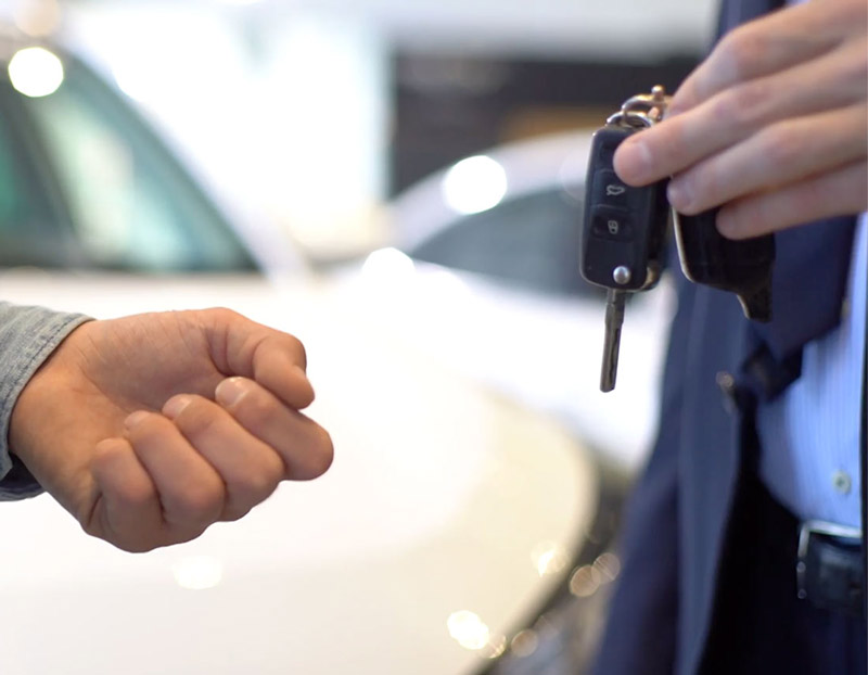 En person räcker över ett par bilnycklar