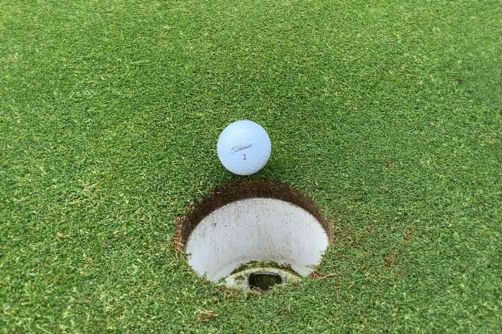 Golfboll bredvid ett hål på en golfbana.