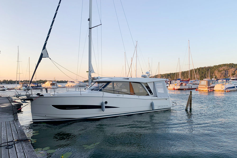 En fin hybridbåt som står parkerad i en hamn bland andra båtar.