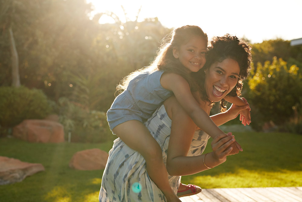 En mamma bär ett barn på sina axlar