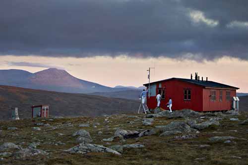 Målare från Nordisk Yta som målar en stuga på ett berg.