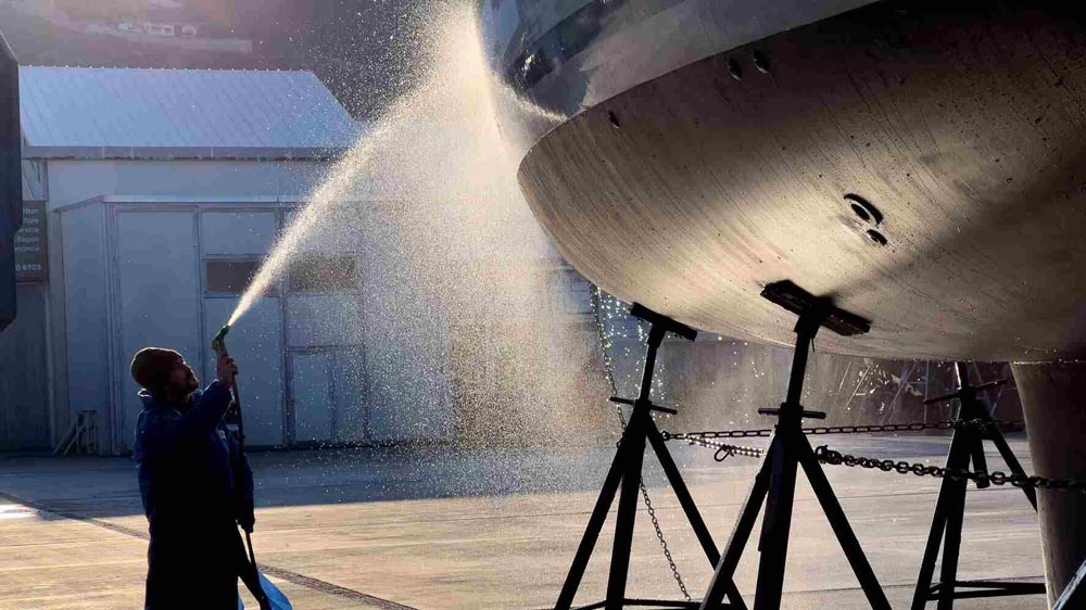 En person spolar av en båt på land